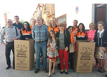 Celia, en el centro entre su madre y el alcalde, presentan los contenedores de latas
